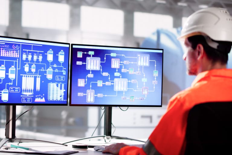 A man wearing an orange shirt and hard hat is engaged in work