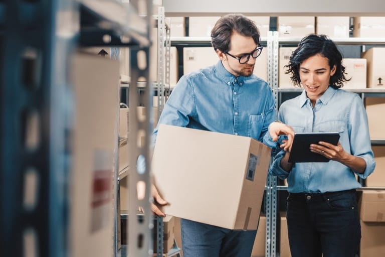 Two people inspecting a box in a warehouse