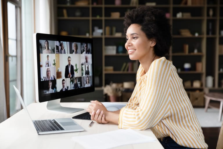 A woman seated at a desk, engaged in a video conference